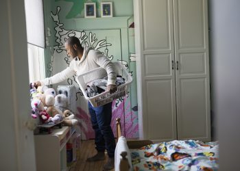 Father carrying laundry basket in child