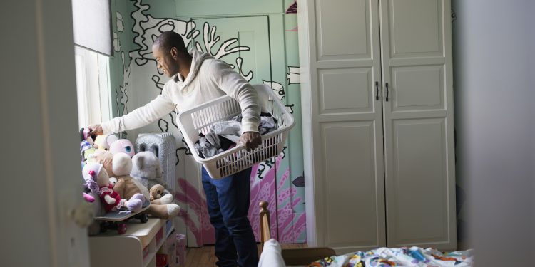 Father carrying laundry basket in child