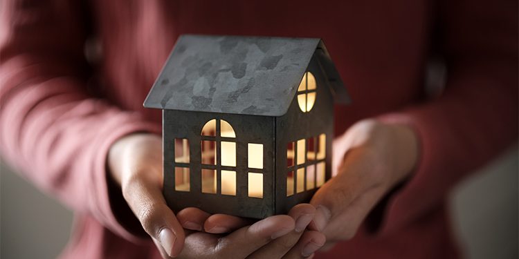 Miniature house model with illuminated light in the hand