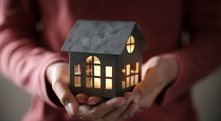 Miniature house model with illuminated light in the hand