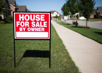 House For Sale By Owner Sign in a front yard of a home