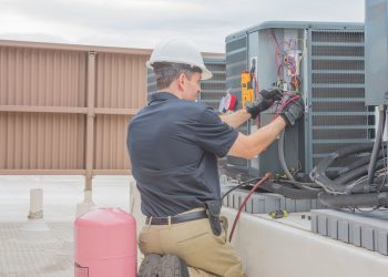 Technician checking for power on a rooftop condensing unit.