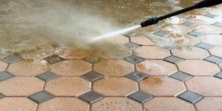 Cleaning concrete block floor by high pressure water jet.