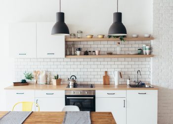 Modern new light interior of kitchen with white furniture and dining table