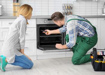 Housewife with worker near oven in kitchen