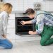 Housewife with worker near oven in kitchen
