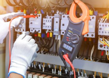 electrician measurements with multimeter tester in control panel.