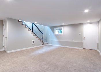 Light grey and spacious basement area with staircase.