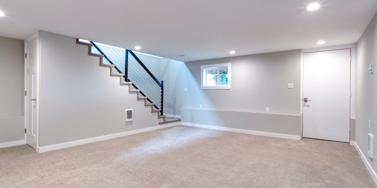 Light grey and spacious basement area with staircase.
