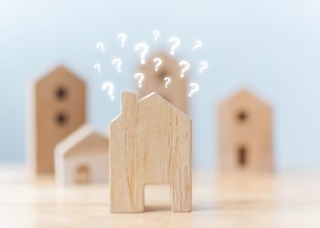 Real estate developer and managing property investment concept. Selective focus wooden houses with question mark on table