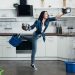 Full length view of shoked woman in jeans dealing with water leak in kitchen