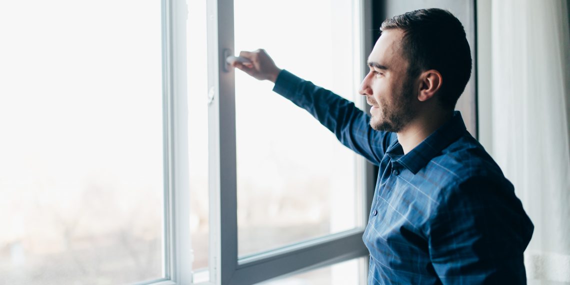 Man is opening the window at home to refresh the room