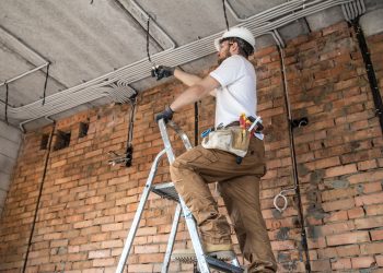 Electrician with tools, working on a construction site. Repair and handyman concept. House and house reconstruction.