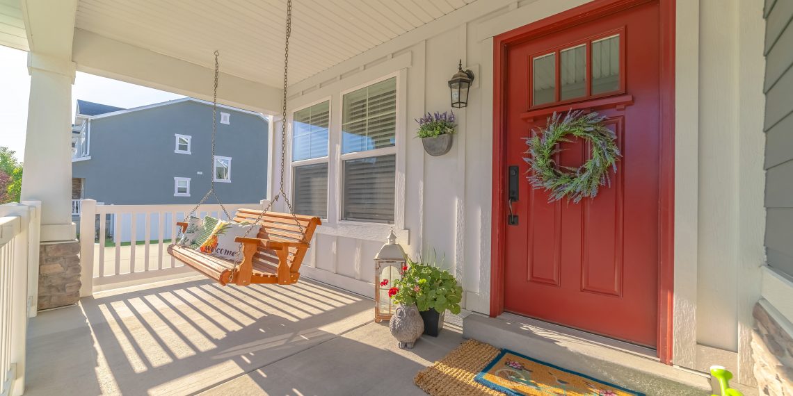 Front porch of modern home with swinging chair. The front porch of a modern home with a wreath on the door and a swinging chair.