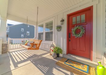 Front porch of modern home with swinging chair. The front porch of a modern home with a wreath on the door and a swinging chair.