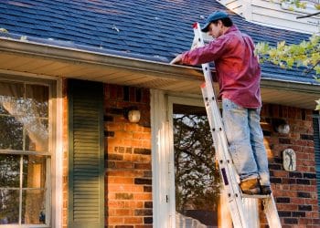 Man Cleaning Gutters on Ladder