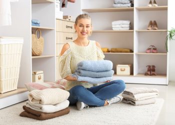 Woman with stacks of clean clothes at home