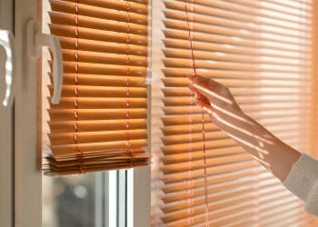 Woman opening blinds on window