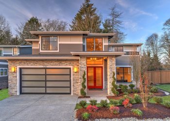 Modern contemporary house exterior with luxury details, landscaping, stone, wood, glass, lots of large windows with evening lights and red front door.