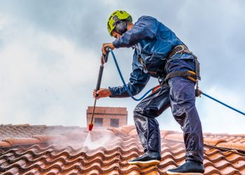 worker washing the roof with pressurized water