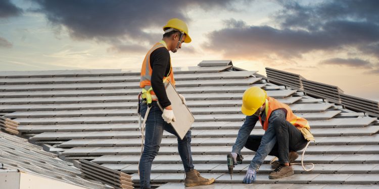 Asian engineer workers install new CPAC roof, roofing tools, electric drill, use on new roof with CPAC roof house construction idea.