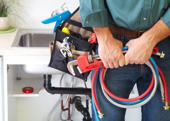 Plumber with Plumbing tools on the kitchen. Renovation.