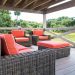 A patio in the tropics with brown rattan furniture and orange cushions