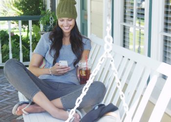 Young woman texting and sitting on porch