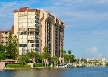 Beautiful waterside waterfront condominium luxury homes on a waterway with boats at the dock and green palm trees