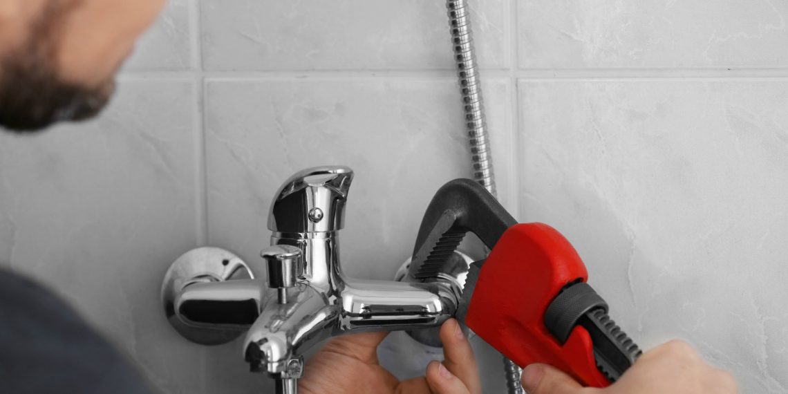 Plumber repairing faucet in shower, closeup