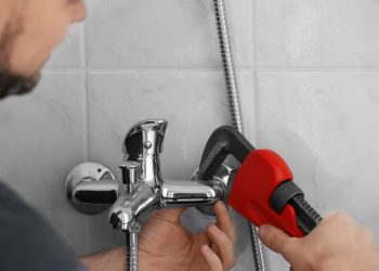 Plumber repairing faucet in shower, closeup