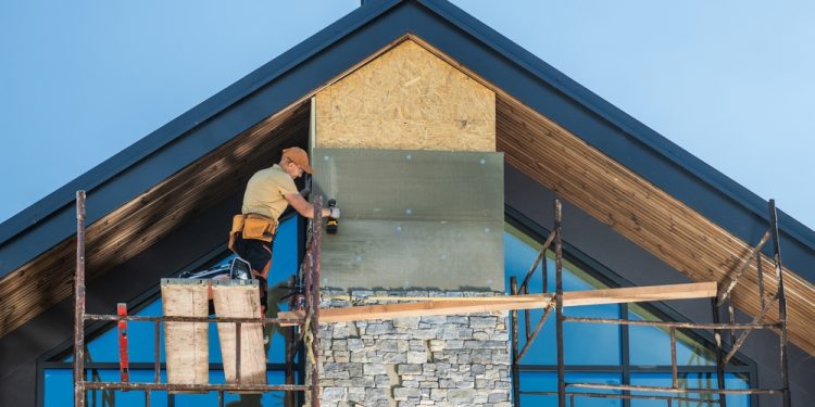 Construction,Worker,Installing,Stone,Veneer,On,A,Modern,Home