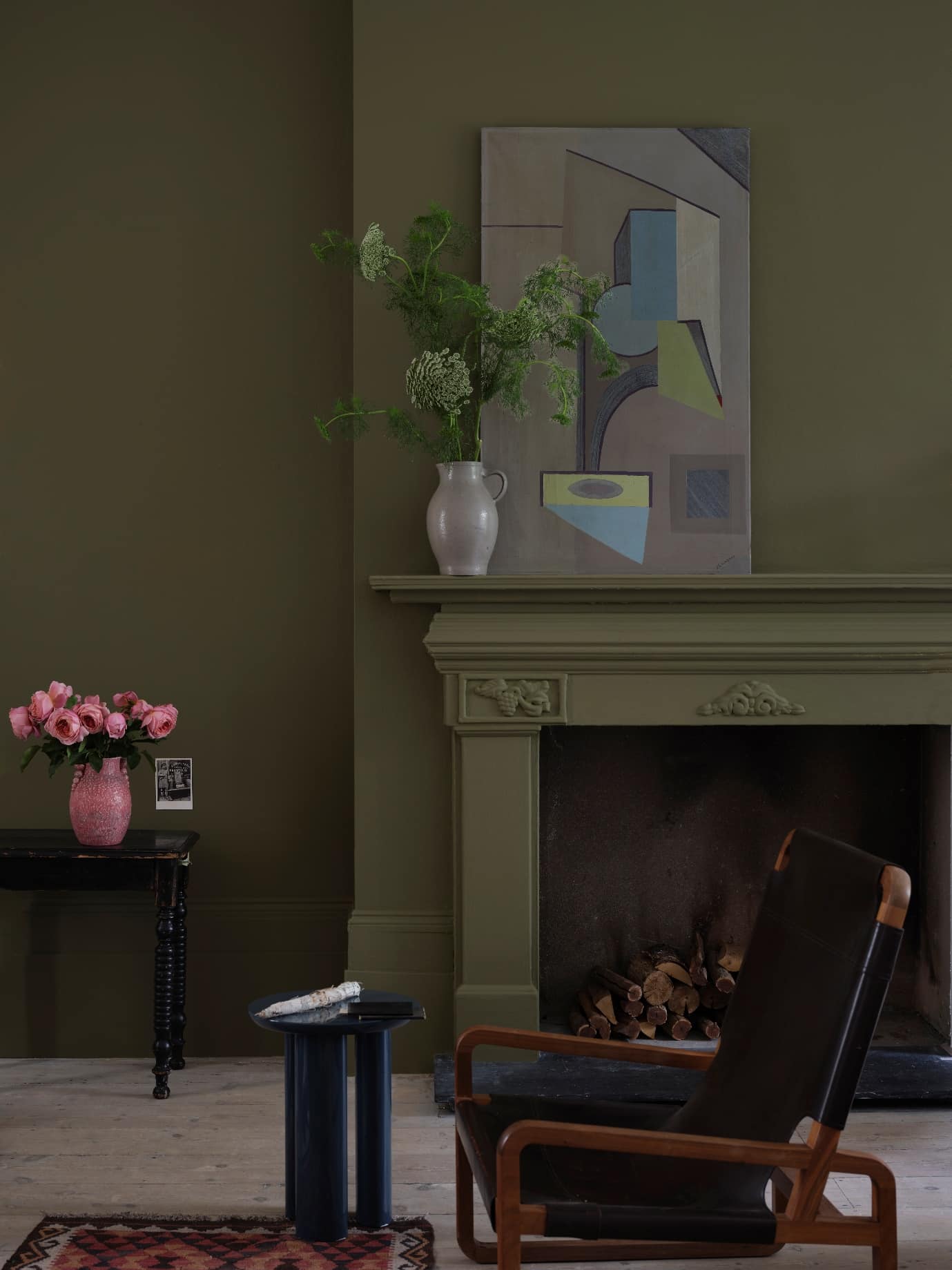 A fireplace with a vase of flowers and a painting on the wall