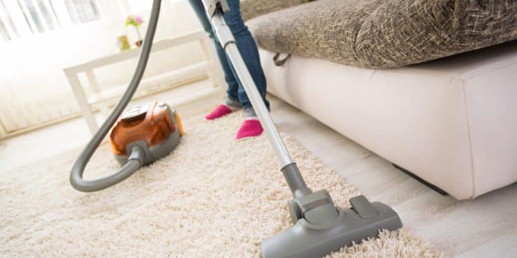 Cleaning carpet with vacuum cleaner in living room