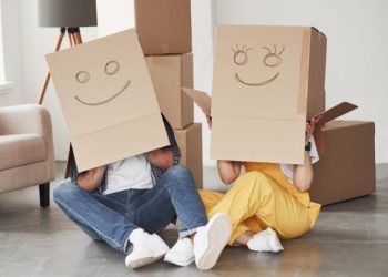 Cute smiles on boxes that is on the heads. happy couple together in their new house. conception of moving Free Photo