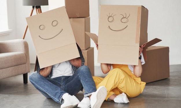 Cute smiles on boxes that is on the heads. happy couple together in their new house. conception of moving Free Photo