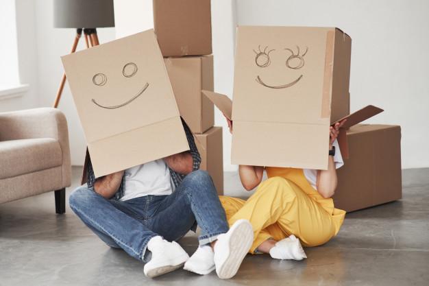 Cute smiles on boxes that is on the heads. happy couple together in their new house. conception of moving Free Photo