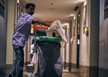 man in blue dress shirt and blue denim jeans holding green plastic bag