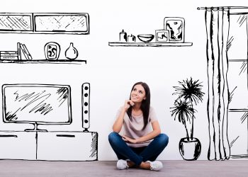 Dreaming about new apartment. Cheerful young woman smiling while sitting on the floor against white background with drawn home interior