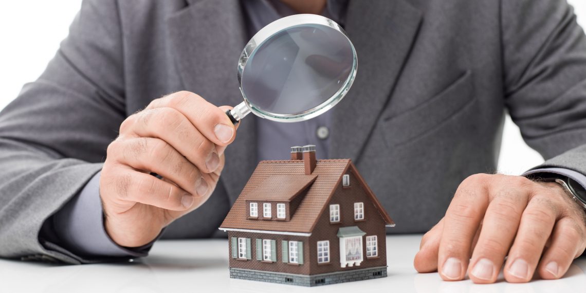 Inspector examining a house using a magnifying glass, house inspection and real estate concept