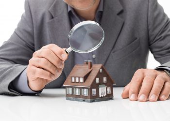 Inspector examining a house using a magnifying glass, house inspection and real estate concept